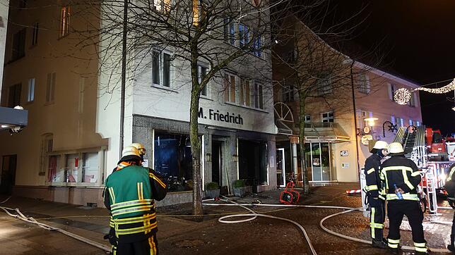 Einsatzkräfte der Feuerwehr stehen am frühen Morgen des 30. Dezembers vor dem ausgebrannten Geschäft in der Karlstraße. (Archivbild)