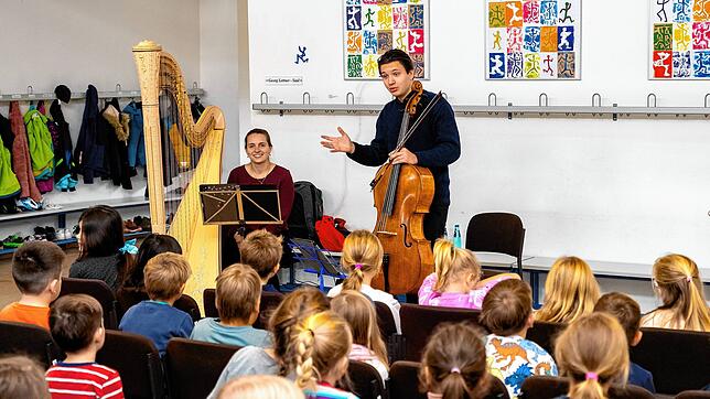 Johanna Dorothea Görißen (links) und Michael Wehrmeyer (rechts) erklären den Schülern in Brigachtal ihre Instrumente. Bild: Hans-Jürgen Götz