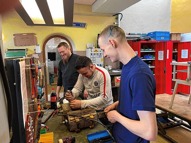 Michael Heß und Joshua Friedrich (rechts) bauen den Umformer auseinander. Ralf vom Verein Elektroseelsorge (links) gibt einige Tipps für ...