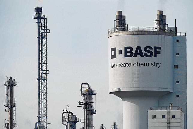 Ein Turm mit der Aufschrift BASF steht neben Schornsteinen auf dem Werksgelände des Chemiekonzerns BASF. Der Konzern investiert seit ...