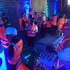 Es ist dunkel, buntes Licht strahlt indirekt an die rohe Wand. Es gibt Häppchen und Getränke. Ministerbesuch oder Untergrund-Party?
