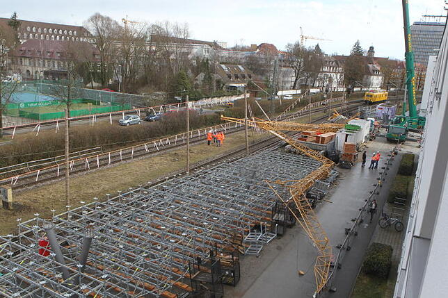 Der Blick aus dem angrenzenden Wohnhaus zeigt den umgestürzten Kran, der in Konstanz über den Gleisen, dem Gerüst des zukünftigen ...