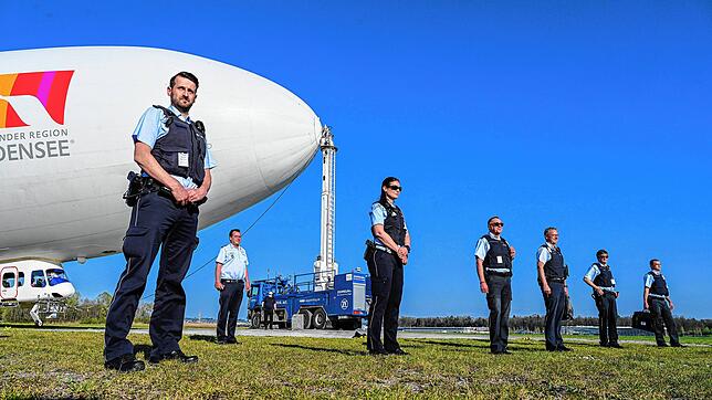 Mehrere Polizisten vor dem Zeppelin NT. Die Beamte kontrollierten von Bord des Luftschiffs aus, ob sich die Menschen an die Regeln zur ...