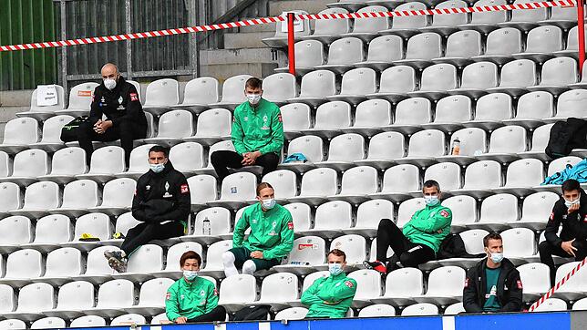 Gähnende Leere auf den Rängen. Die Ersatzspieler von Bremen sitzen verteilt im Schwarzwald-Stadion und tragen Mundschutz und verfolgen ...
