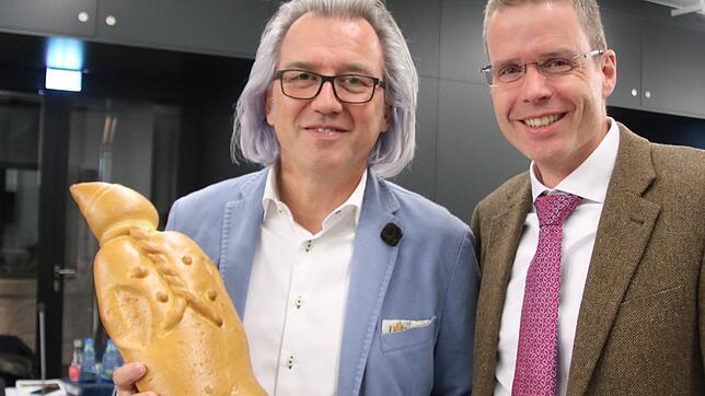 Für den hungrigen CDU-Fraktionssprecher: Konrad Hall wird von Bertolt Wagner mit einem riesen Weckenmann versorgt.