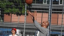 Grünen-Politiker Danyal Bayaz (rechts) wirft auf einem Basketballplatz in Stuttgart den Ball Richtung Korb. Links neben ihm ...