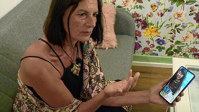 Orly Louk, Tante der 22-jährigen Shani Louk, sitzt auf einer Couch und zeigt ein Handyfoto ihrer Nichte.