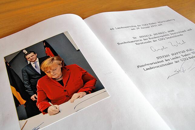 Kanzlerin Angela Merkel trägt sich in das Goldene Buch ein. Im Hintergrund der damalige Oberbürgermeister Thorsten Frei.