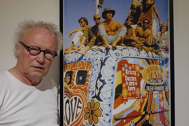 Kurator Reinhard Schultz mit einem Foto von Hippies auf einem Bus.