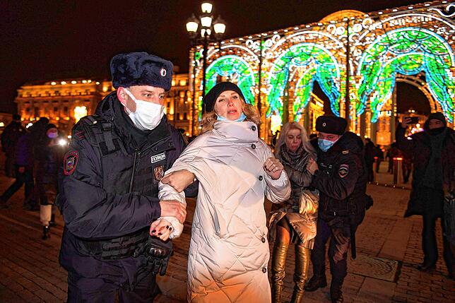 Polizisten führen eine Frau ab, die in Moskau gegen Russlands Invasion demonstriert.