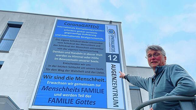 Jens Eckert, Augenarzt aus Villingen-Schwenningen, zeigt auf sein Plakat. Dieses hängt am Haus, in dem er seine Praxis betreibt.