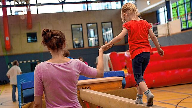 Eltern und Kinder beim Turnen in einer Sporthalle (Symbolbild).