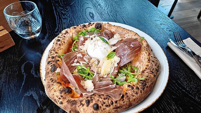 Die Pizza mit Rucola, Parmaschinken und Parmigiana.
