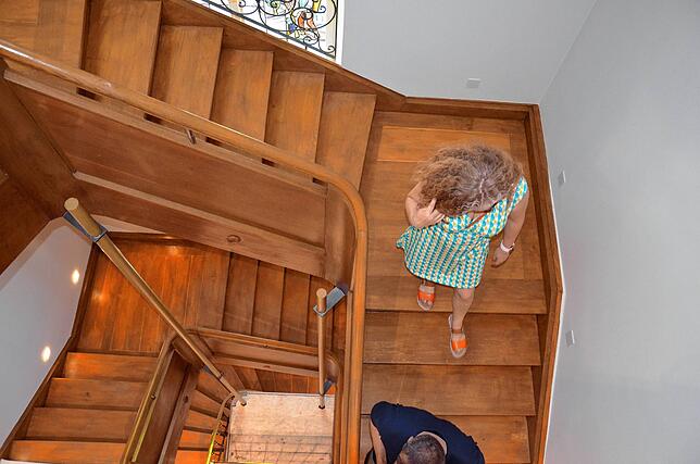 Gäste laufen auf der historischen Treppe wieder Richtung Erdgeschoss. Sie wurde im Zuge der Sanierung instandgesetzt.