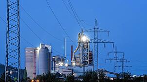 Strommasten stehen im Morgenlicht vor einem Zementwerk in Rottweil.