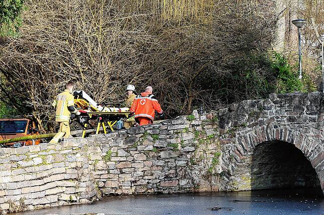 Rettungskräfte gehen in der Nähe des Tatortes eine kleine Brücke hinauf.