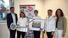 Bürgermeister Ralph Gerster (von links) gratuliert dem Team der Stadtbücherei zum 25-Jährigen und überreicht einen limitierten ...