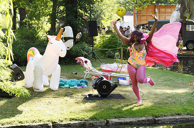 Dragqueen Le Gateau Chocolat tanzt am Weiher vor dem Festspielhaus.