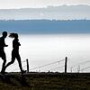 Jogger laufen am Bodensee in Richtung Meersburg. Schon eine kurze tägliche Sporteinheit fördert die Gesundheit und das Wohlbefinden.