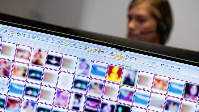 Eine Ermittlerin sitzt vor Monitoren mit unkenntlich gemachten Fotografien, die teilweise sexuellen Missbrauch zeigen. Dieses Symbolbild ...