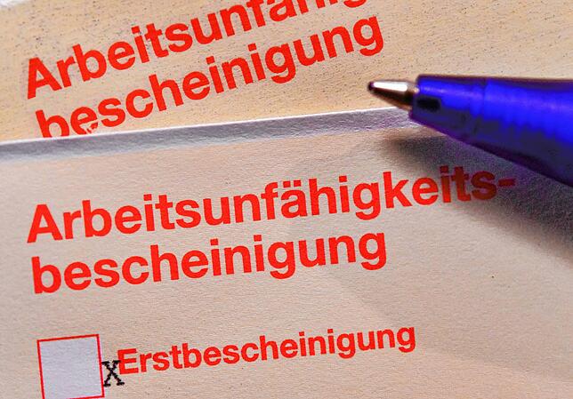 Eine Arbeitsunfähigkeitsbescheinigung, auch Krankschreibung oder “Gelber Schein„ genannt, liegt auf einem Tisch.