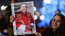 Eine Frau hält ein Bild des verstorbenen Benedikt XVI. vor Beginn der öffentlichen Trauermesse auf dem Petersplatz.
