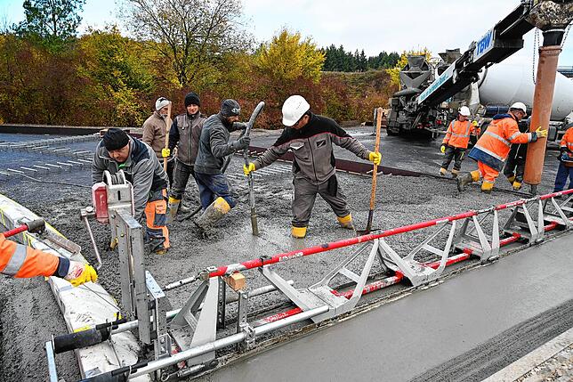 Alle Hände voll zu tun haben die Bauarbeiter bei der Anlieferung des speziellen Fahrbahnbetons.