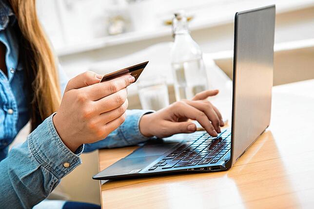 Eine Frau sitzt mit einer Kreditkarte am Laptop. Mit den Daten sollte man sorgsam umgehen, nicht nur bei der Urlaubsbuchung.