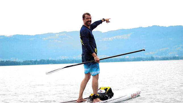 Dario Aemisegger auf seinem Stand-up-Paddle mit den österreichischen Voralpen im Hintergrund.