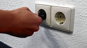 Eine Frau steckt einen Stecker in eine Steckdose: Stromversorgung ist heutzutage eine Selbstverständlichkeit. Stromausfälle können ...