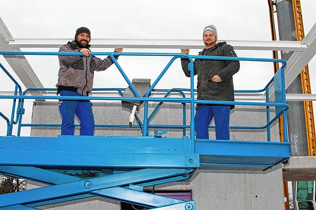 Gute Laune: Zwei Arbeiter der Rheinfelder Firma Horstmann Metallbau auf der Hebebühne stehen vor dem Rohbau des neuen Clubheims.