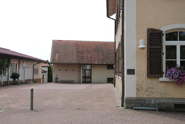 Dorfplatz 2018: (von rechts nach links) Schulhaus, „Musikhüsli“ mit Kindergartenraum, Musikprobelokal und Raum für die Feuerwehr, ...