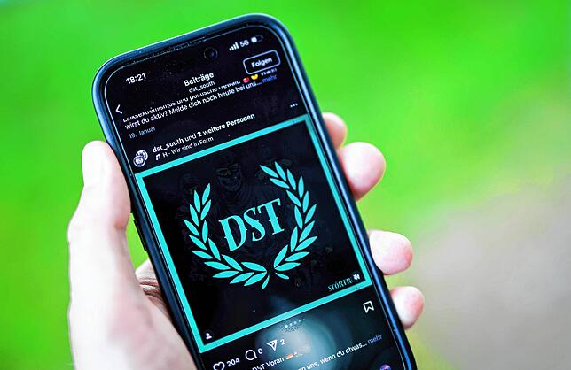 Ein junger Mann hält ein Smartphone in der Hand, auf der die Instragram-Seite von „Sturmtrupp Süd“ zu sehen ist.
