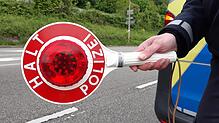 Ein Polizist hält eine Kelle, um das Anhalten zu signalisieren.