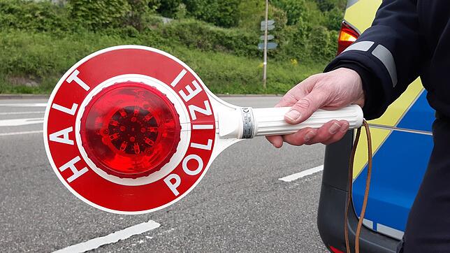 Ein Polizist hält eine Kelle, um das Anhalten zu signalisieren.