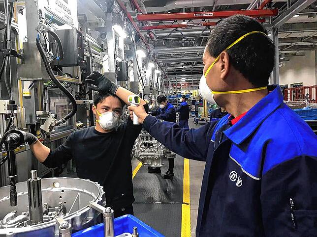 Mitarbeiter in einem ZF-Werk in China tragen Atemschutzmasken und messen Fieber.