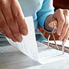Eine Seniorin ordnet Papiere ein. In Zeiten steigender Kosten erhoffen sich Ältere von einem Hausverkauf finanzielle Entlastung.
