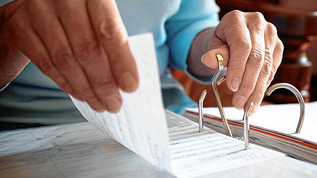 Eine Seniorin ordnet Papiere ein. In Zeiten steigender Kosten erhoffen sich Ältere von einem Hausverkauf finanzielle Entlastung.