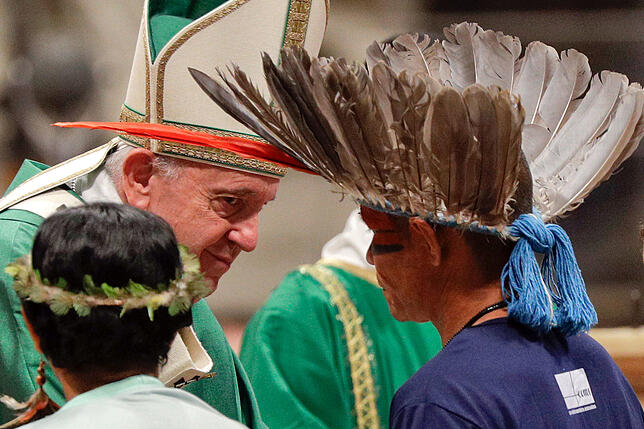 Mitglieder eines indigenen Volkes mit bemalten Gesichtern und Federschmuck am Kopf treffen auf Papst Franziskus während der ...
