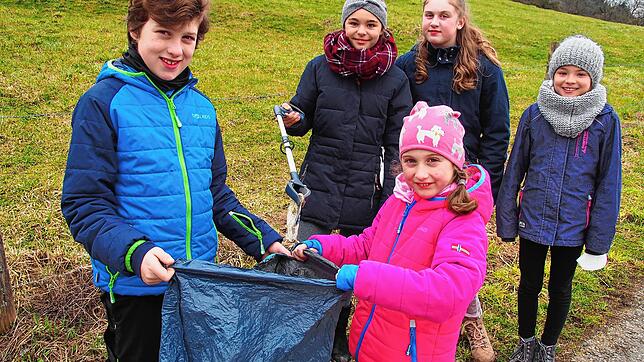 Joah und Grace Fodor halten den Müllsack, während Amelie Fahr einen Müllschnipsle, den sie mit der Zange aufgesammelt hat, hineinwirft. ...
