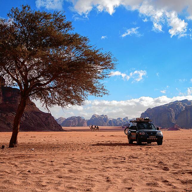Dakar, so haben Anouk Köpfer und Camillo Pohl ihr Auto genannt, in der roten Wadi Rum Wüste mit Kamelen im Hintergrund.