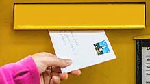 Eine Frau wirft einen Brief in einen Briefkasten. (Symbolbild)