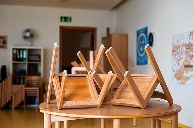 Hochstellte Kinderstühle auf dem Tisch einer Kindertagesstätte.