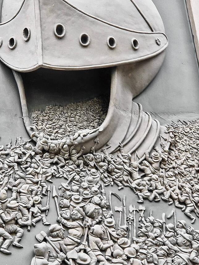 Auf dem Relief zur Böblinger Schlacht stürzen Tausende in den tödlichen Schlund des Kriegshelms.