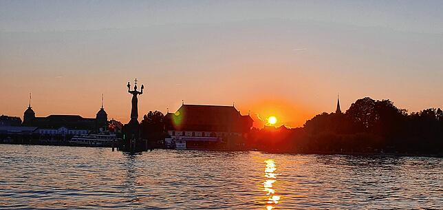 Die Sonne, der Stern, der der Erde am nächsten ist und das Zentrum des Sonnensystems bildet, verabschiedet sich hinter der Skyline von ...