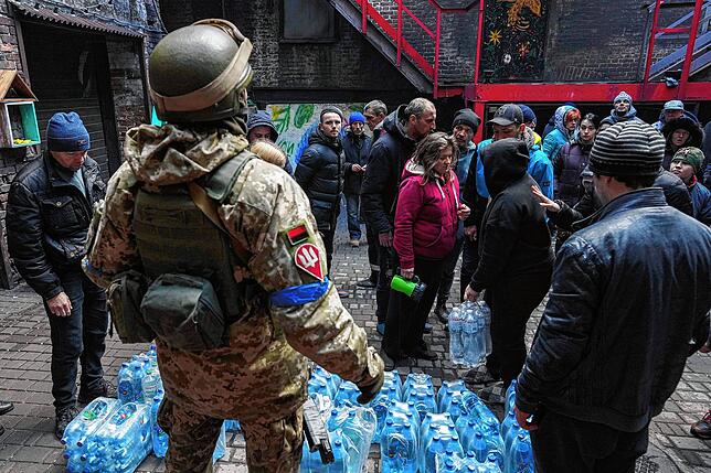 Ein ukrainischer Soldat verteilt im belagerten Mariupol Wasser an Zivilisten.