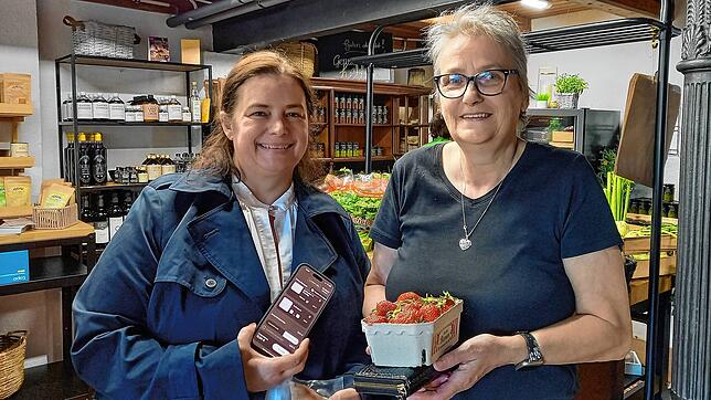 Nicole Claußnitzer, Inhaberin des Geschäfts „Genussreise“, erläutert ihrer Kundin Marlies Seetz, wie sie per App künftig den Laden ...