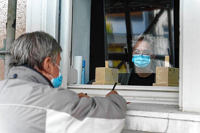Die Wohnungslosen – wie hier Dieter Rattke – werden von Sozialarbeiterin ... durch ein Fenster beraten.