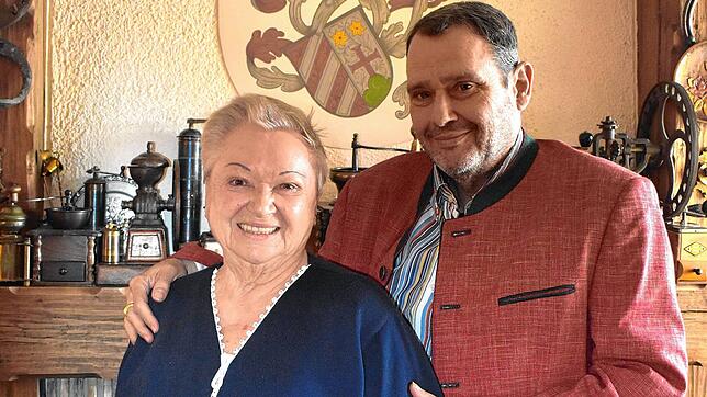 Lore Stadelhofer mit ihrem Sohn Hermann vor dem Familienwappen.