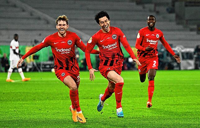 Frankfurts Daichi Kamada (M) bejubelt sein Tor zum 2:1 mit Christopher Lenz (l) und Evan Ndicka.